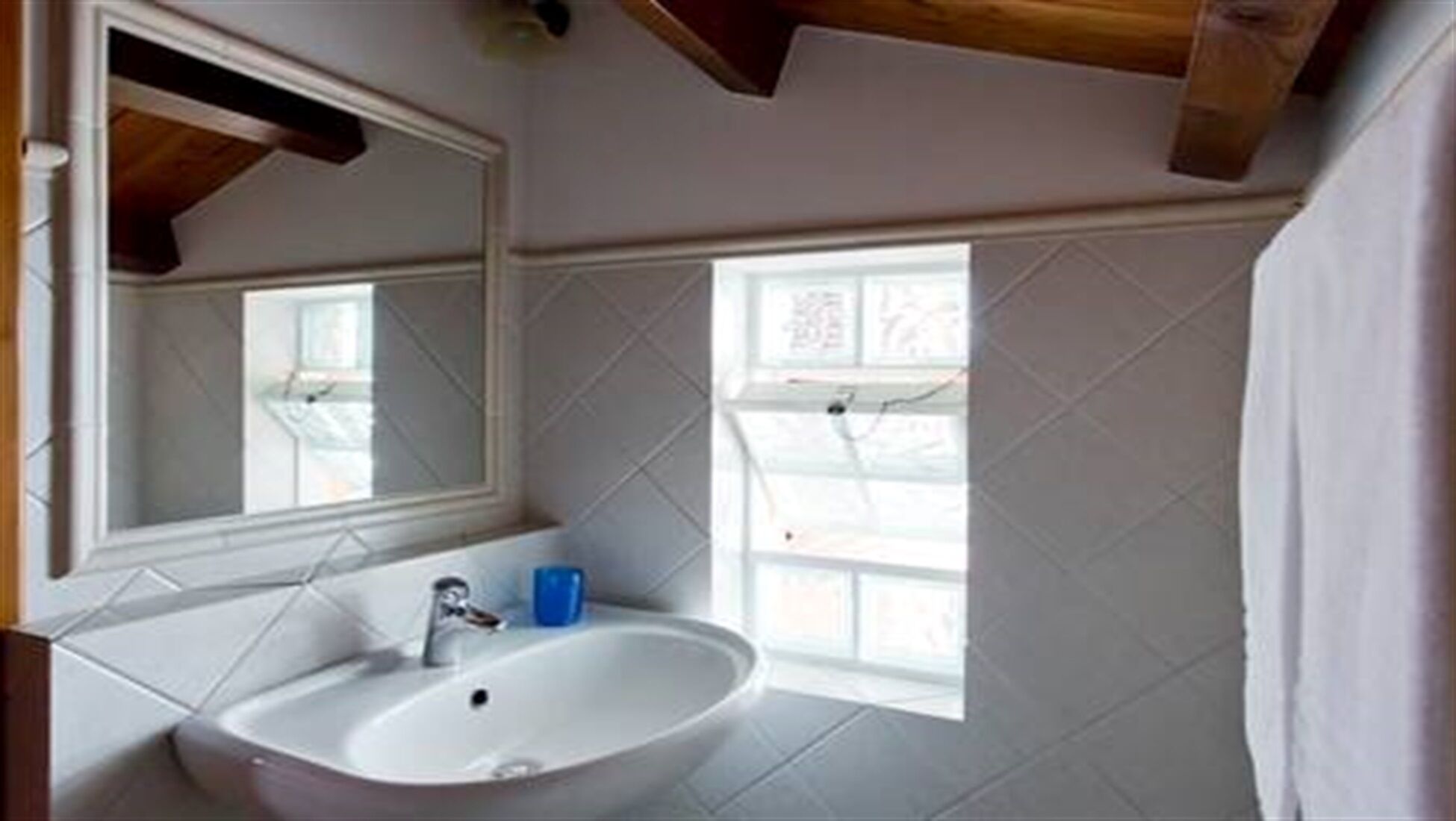 A bathroom with a white sink, a mirror, and a window.