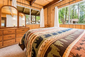 Une chambre à coucher avec un lit, une commode, un miroir et une fenêtre avec des rideaux.