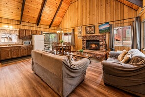 Un intérieur de chalet chaleureux avec un coin repas, une cheminée et un plancher en bois.