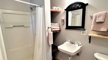 Une salle de bain équipée d’une douche, d’un lavabo, de toilettes et d’un miroir.