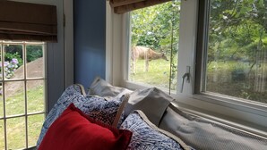 A room with a large window, a view of a garden, and a bed with patterned bedding. - Your private getaway! (Gibsons)