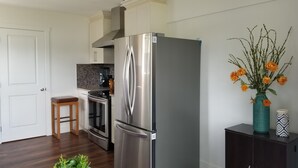 A modern kitchen with a stainless steel refrigerator, a wooden stool, and a tiled backsplash. - Your private getaway! (Gibsons)