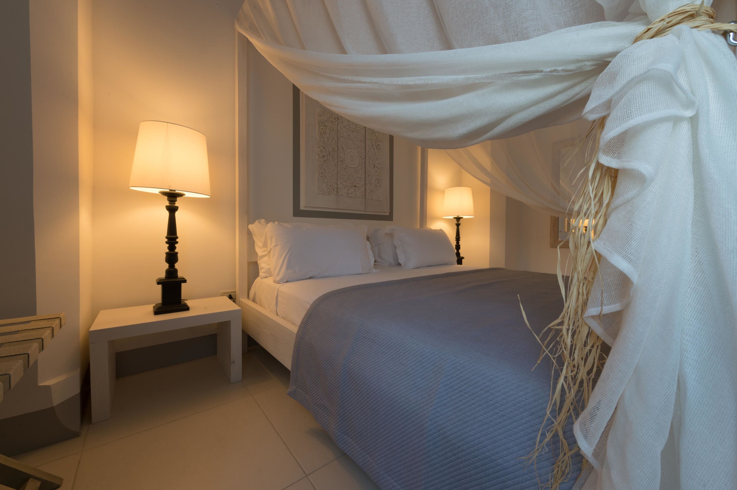 Una camera da letto ordinata con un letto, lampade sui comodini e un elemento decorativo a parete.