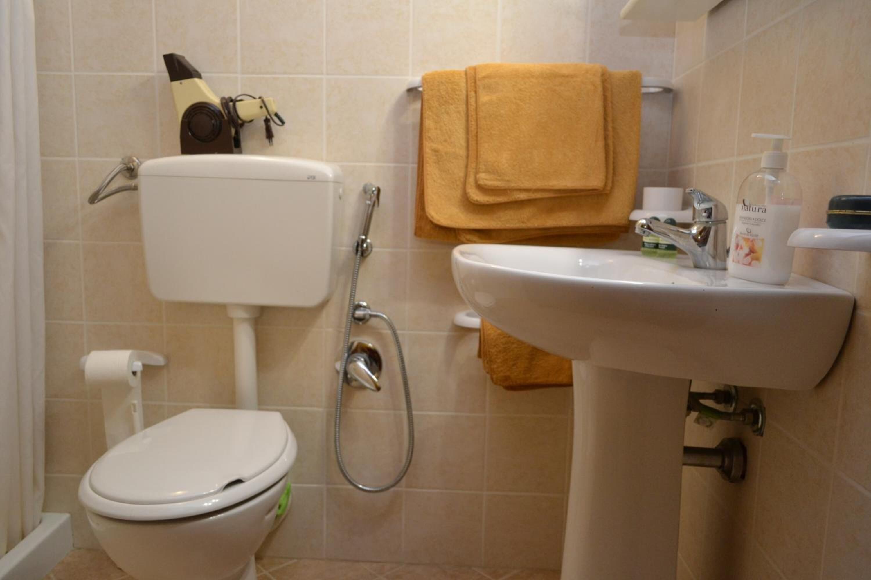 Un baño con inodoro, ducha, lavabo y una toalla colgada en la pared.
