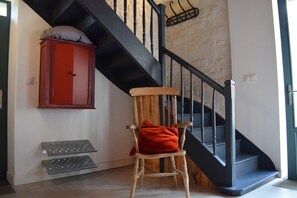 Ein Holzhocker mit rotem Kissen in einer Diele mit Treppe.