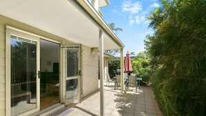 A covered patio with a sliding glass door, outdoor furniture, and a red umbrella. - Cavalier (Zeally Bay Rd): 4  BR, 2  BA House in Torquay, Sleeps 9 (Torquay)