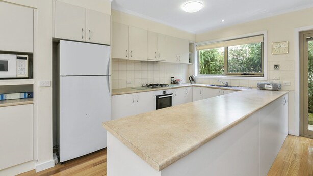 A modern kitchen with white cabinets, a built-in oven, a microwave, and a large window providing natural light. - Cavalier (Zeally Bay Rd): 4  BR, 2  BA House in Torquay, Sleeps 9 (Torquay)
