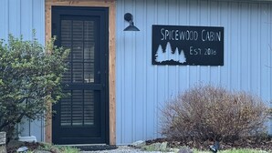 A building with a black door and a sign that reads "Spicewood Cabin Est. 2018".