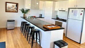 Een moderne keuken met witte kasten, een zwart aanrecht en een geïntegreerd eiland met barstoelen.
