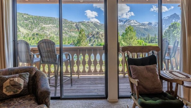 Une chambre dotée d’une porte-fenêtre coulissante donnant sur un balcon avec vue sur les montagnes.