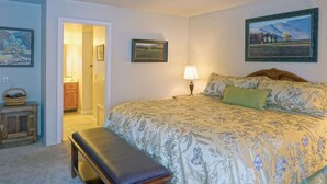 A bedroom with a bed, a bench, a lamp, and framed pictures on the walls. - June Lake Interlaken 12 Cozy, Spacious (June Lake)