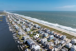 An aerial view of a coastal residential area with houses, a marina, and a beach.