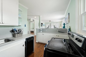 A compact kitchen with white cabinets, a black stove, and a dishwasher. - 710 Canal Upper - Make Everyday a Holiday! (Carolina Beach)