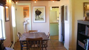 A dining area with a wooden table and chairs, a bookshelf, and a framed picture on the wall.