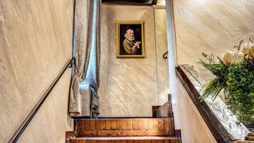 A staircase with a framed portrait on the wall, a potted plant, and a textured wall.