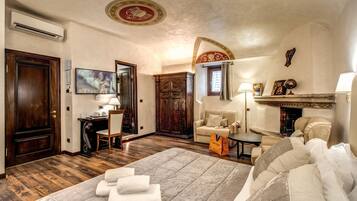 Camera d'albergo con un letto grande, una scrivania, una sedia, un divano e un camino.
