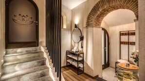 Entrada moderna a un spa de bienestar, con una escalera de piedra, un mostrador de recepción y un tocador de madera.