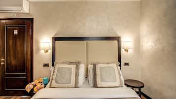 Una camera d'albergo con un letto grande, due abat-jour, una porta in legno e un condizionatore d'aria.