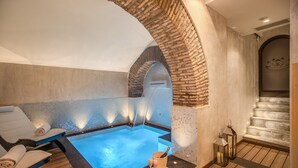 Un área de spa con jacuzzi, sillas de descanso y suelo de madera.
