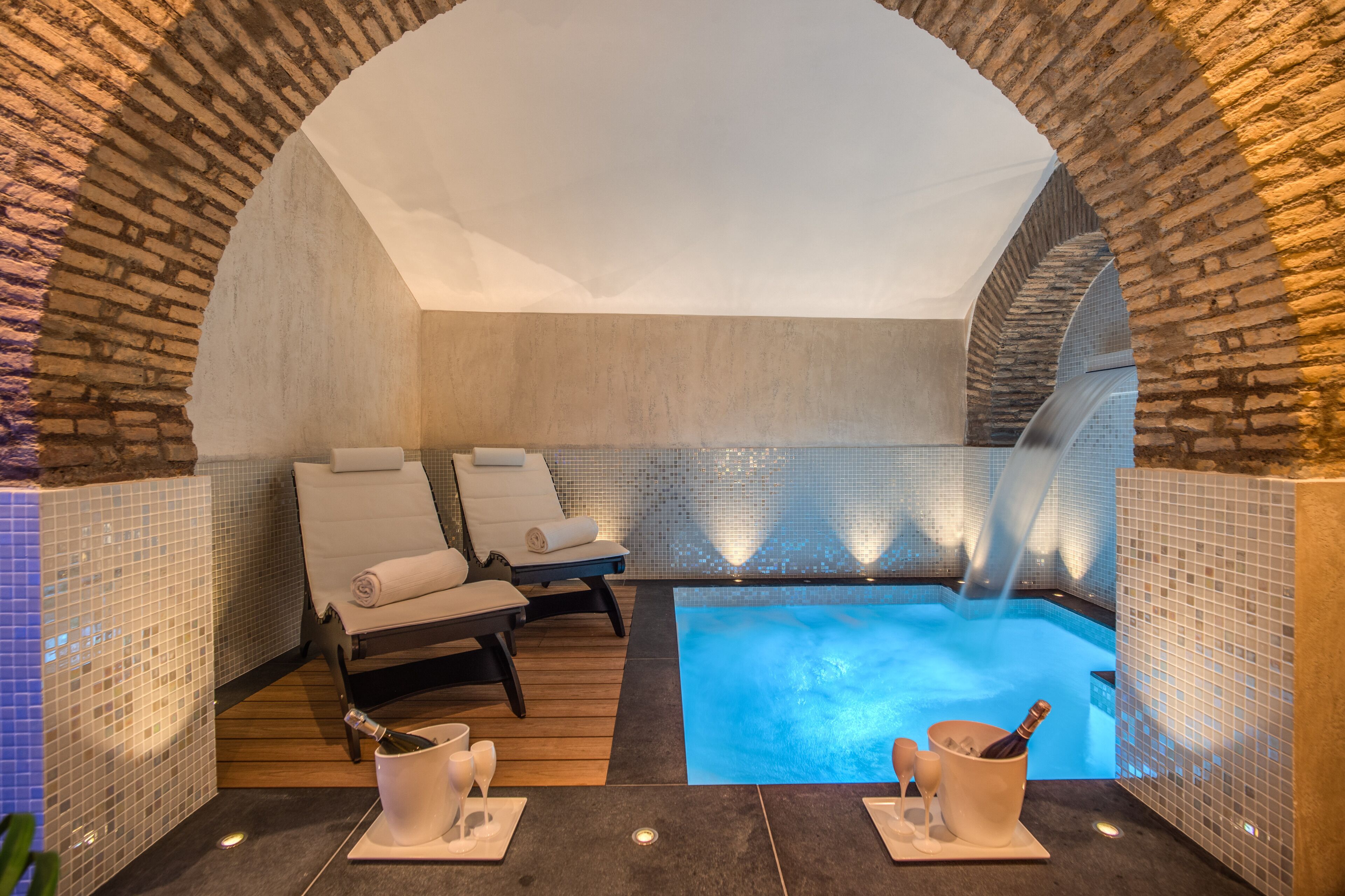 Un área de spa con una bañera de hidromasaje, dos sillones reclinables y una botella de champán.