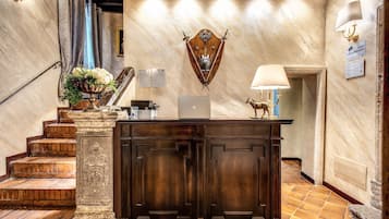 A reception area with a wooden desk, a laptop, and a decorative shield on the wall.