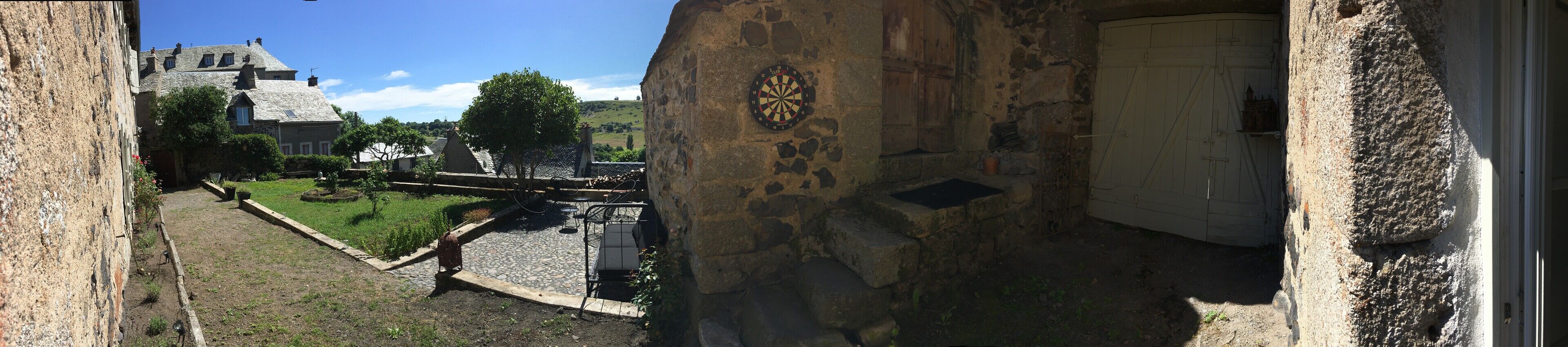 A courtyard with stone walls, a dartboard, and a rustic building in the background.