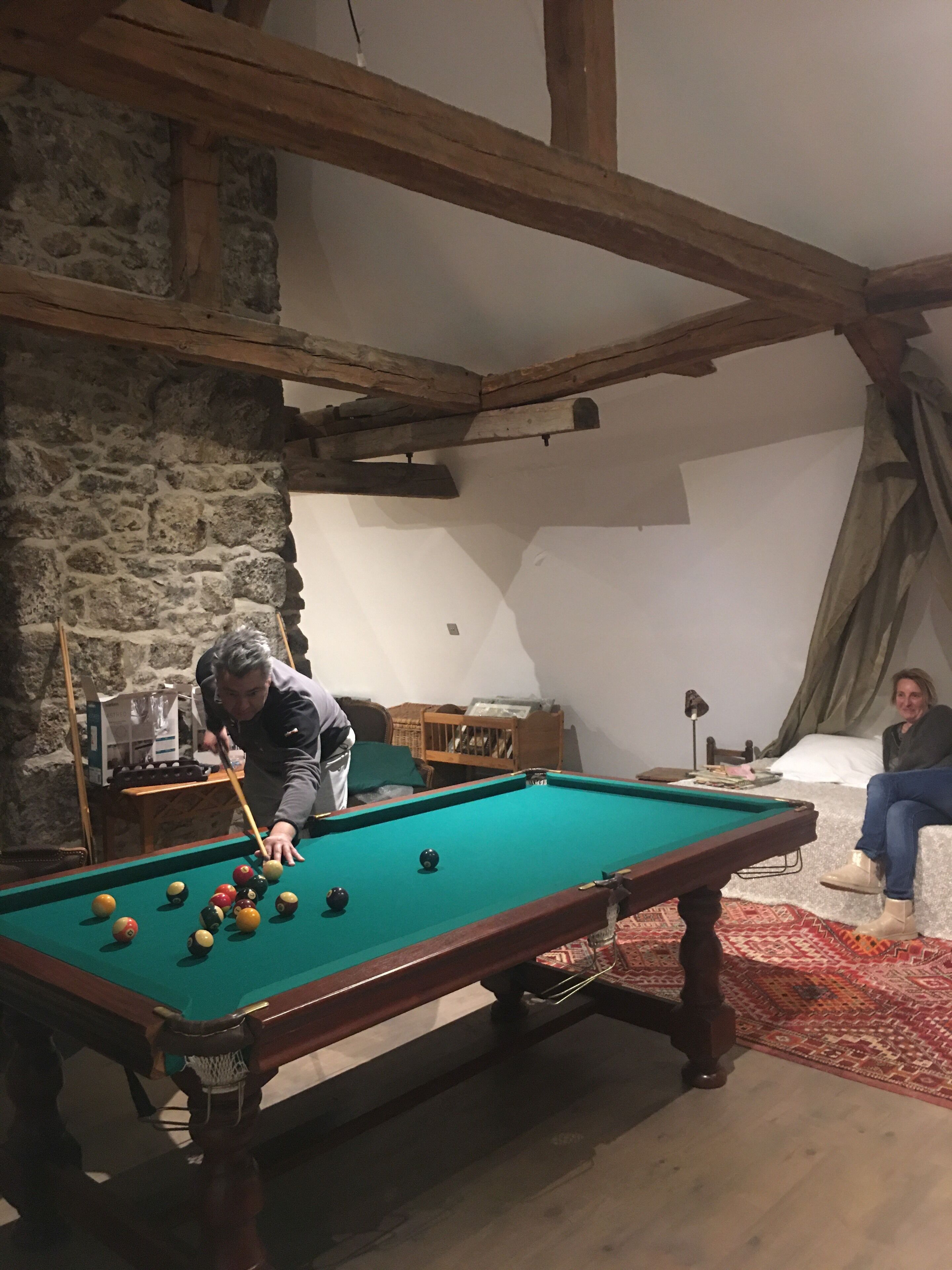 A pool table in a room with stone walls and wooden beams.