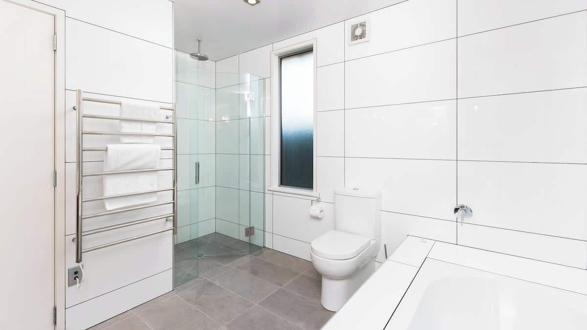 A modern bathroom with a glass-enclosed shower, a toilet, and a bathtub.