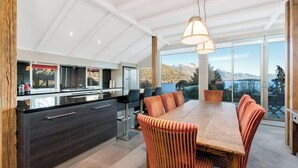 A modern kitchen with a central island, dining area with striped chairs, and large windows offering a mountain view.