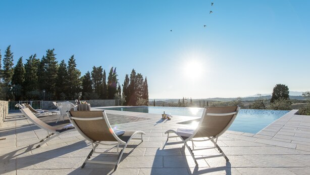 Uma área à beira da piscina com espreguiçadeiras e vista para a piscina.