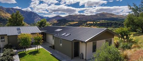 A modern house with a sloped roof, surrounded by a well-maintained lawn and a view of mountains.