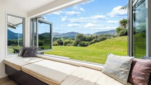 Ein Zimmer mit einem großen Fenster und Blick auf eine grüne Landschaft und Hügel.