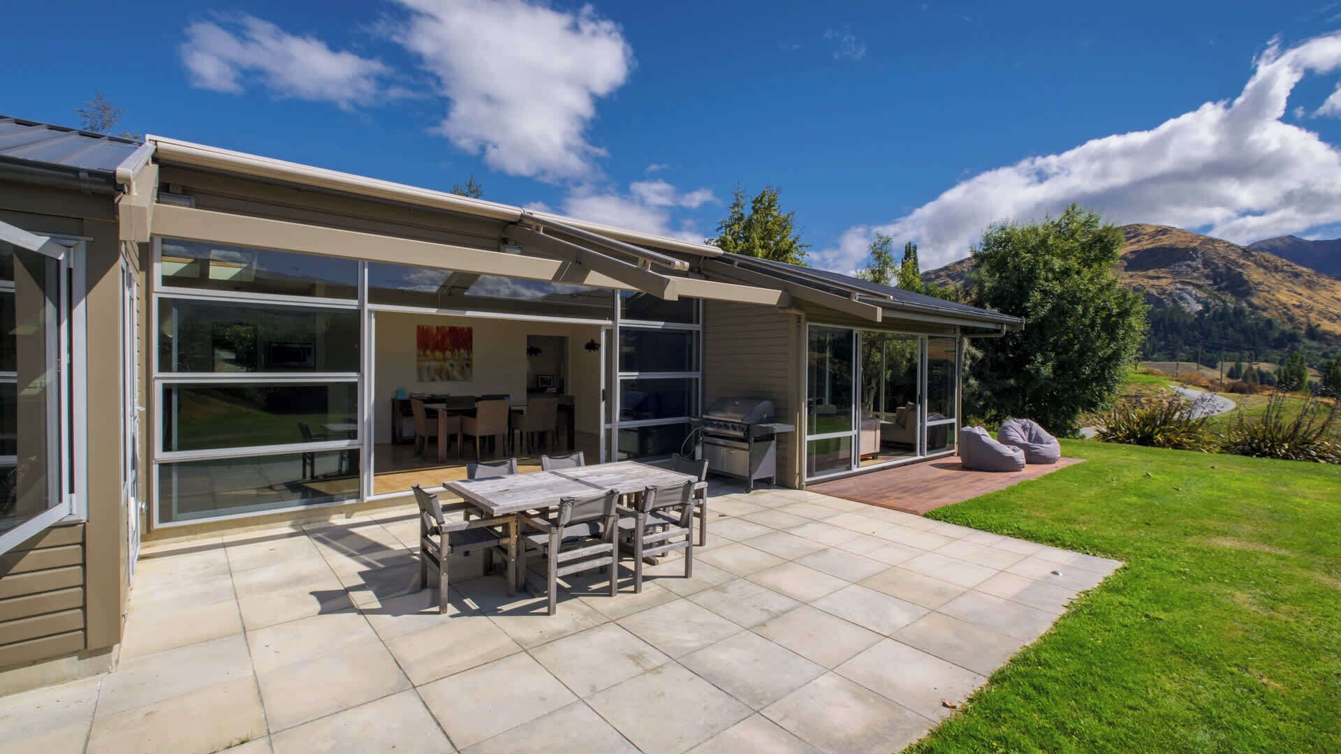 Ein modernes Haus mit Terrasse, Essbereich und Grill.