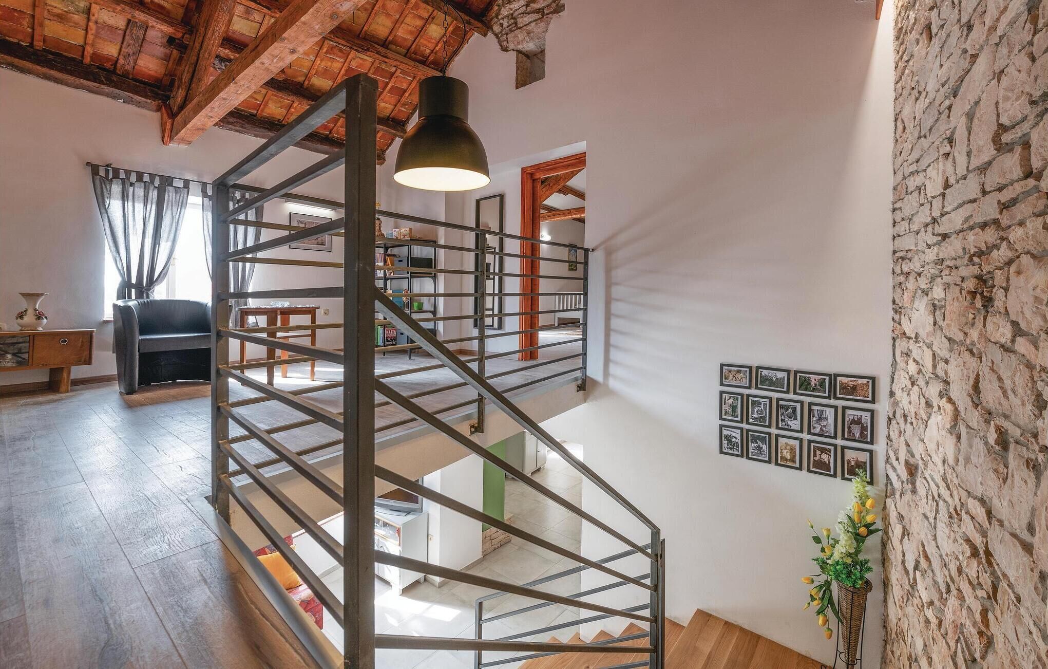 Un intérieur à plusieurs niveaux, doté d’un escalier en colimaçon, de planchers en bois, d’un canapé, d’une table et d’un mur orné de tableaux encadrés.