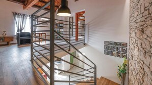 A multi-level interior with a spiral staircase, wooden flooring, a sofa, a table, and a wall with framed pictures. - Amazing home in Hreljici (Hreljici)
