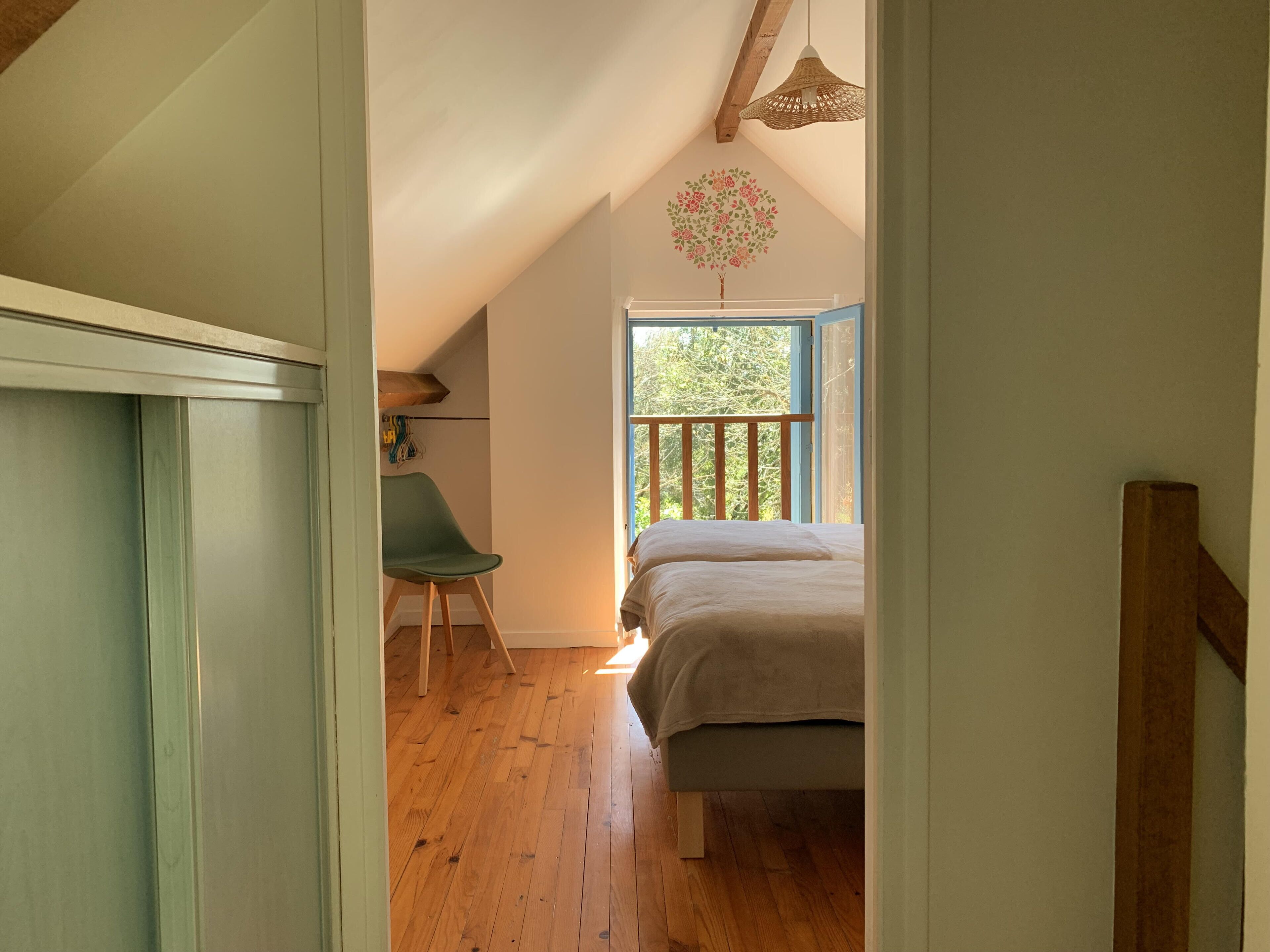 Une chambre à coucher avec un lit, une chaise et une fenêtre donnant sur des arbres.