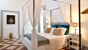 A four-poster bed with a white canopy, a bedside table with a lamp, and a patterned rug. - Dimora Duchessina (Minervino di Lecce)