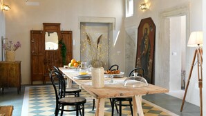 A dining area with a wooden table, chairs, and a checkered floor. - Dimora Duchessina (Minervino di Lecce)