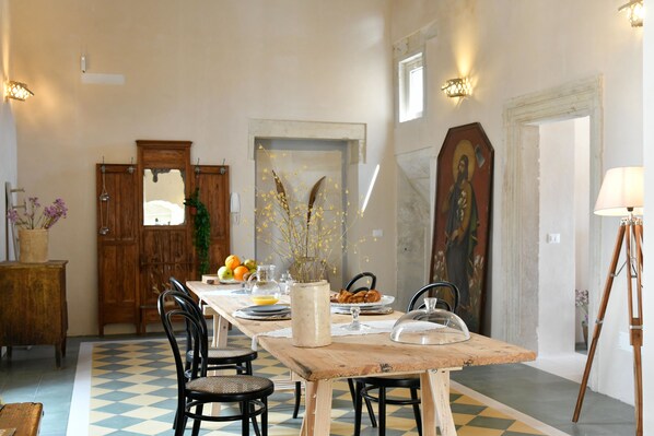 A dining area with a wooden table, chairs, and a checkered floor. - Dimora Duchessina (Minervino di Lecce)