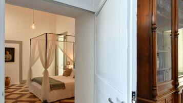 A bedroom with a four-poster bed, a bedside lamp, and a large mirror.