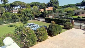 Un barrio residencial con camino pavimentado, coches aparcados y abundante vegetación.