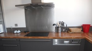 A modern kitchen with stainless steel appliances, wooden countertops, and a built-in dishwasher.