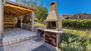 Un patio al aire libre con chimenea de piedra, un banco de madera y una zona de estar cubierta.