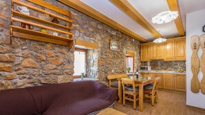 Un interior acogedor con pared de piedra, muebles de madera y una zona de cocina.