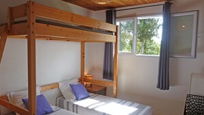 Et soveværelse med køjeseng, vindue og gardiner.