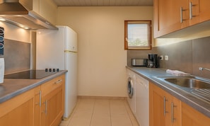 A compact kitchen with a refrigerator, microwave, coffee maker, and a washing machine.