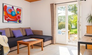 Ein Wohnzimmer mit einer Couch, einem Couchtisch, einem Gemälde und einer Schiebetür, die zu einem Außenbereich führt.