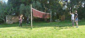 A netted area for sports, surrounded by trees and a wooden fence.