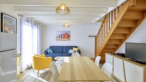A modern living room with a wooden staircase, a dining table, and a sofa. - House with garden, 8 minutes Beach LA BAULE, residence with swimming pool (Guérande)