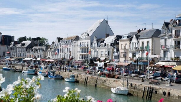 A harbor with boats docked, a prominent building with a pointed roof, and a row of white buildings with balconies. - House with garden, 8 minutes Beach LA BAULE, residence with swimming pool (Guérande)